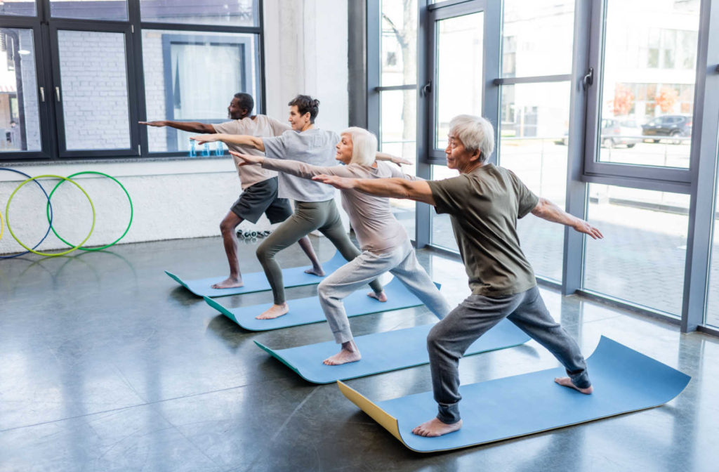 A group of seniors doing balance exercises at the gym.