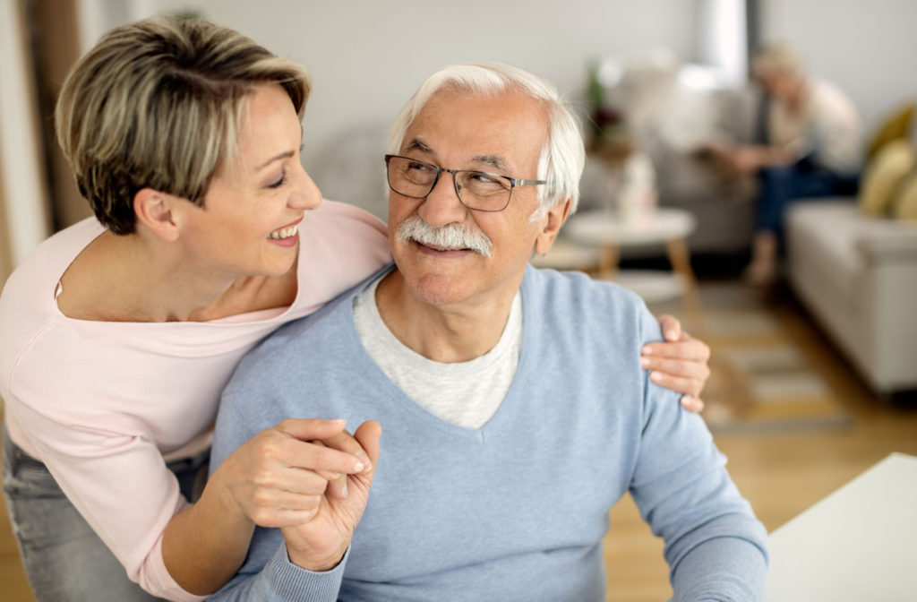 A senior father and his daughter holding hands while talking at home.