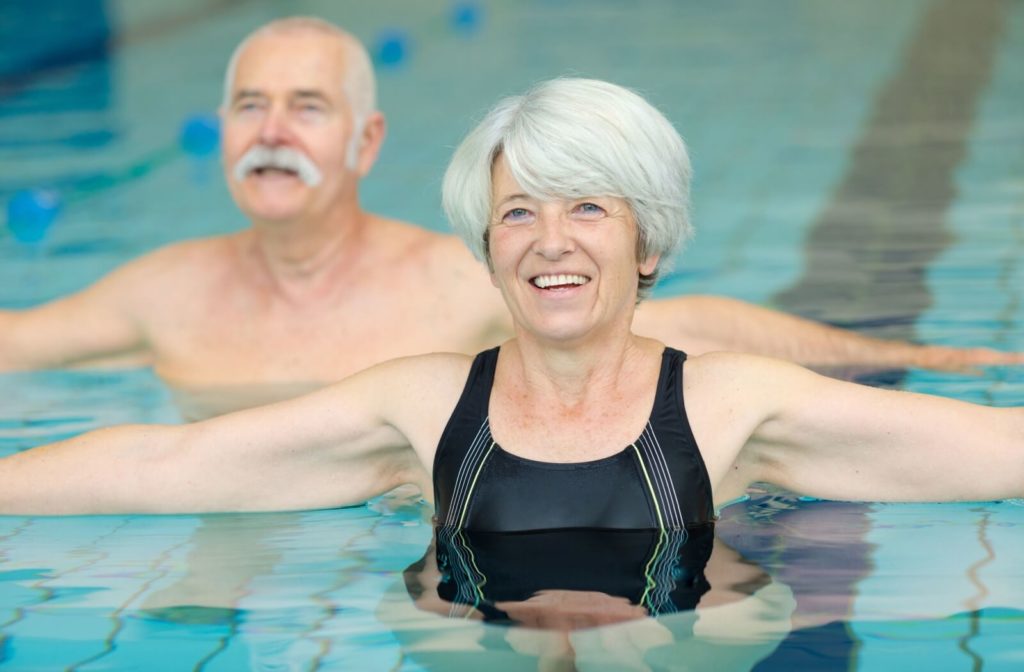 Two older adults exercising in the swimming pool.