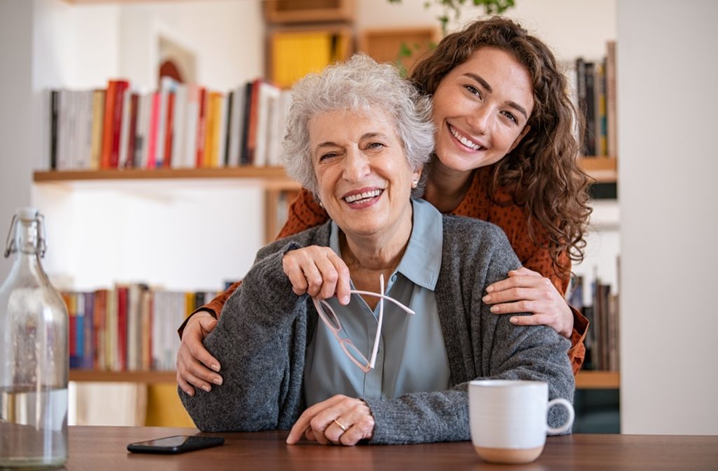 An adult child happily embracing their mature parent in assisted living.