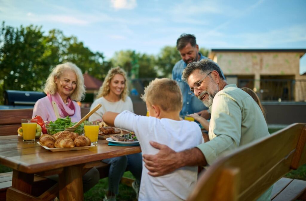 Seniors visit with their family outside for a picnic.