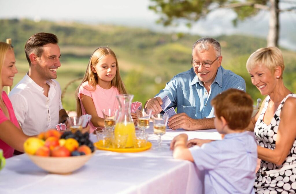 A grandparent plays an easy game of cards with multiple generations of their family.