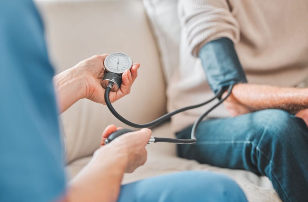 A caregiver uses a hand-pump blood pressure cuff to check a senior’s blood pressure in assisted living