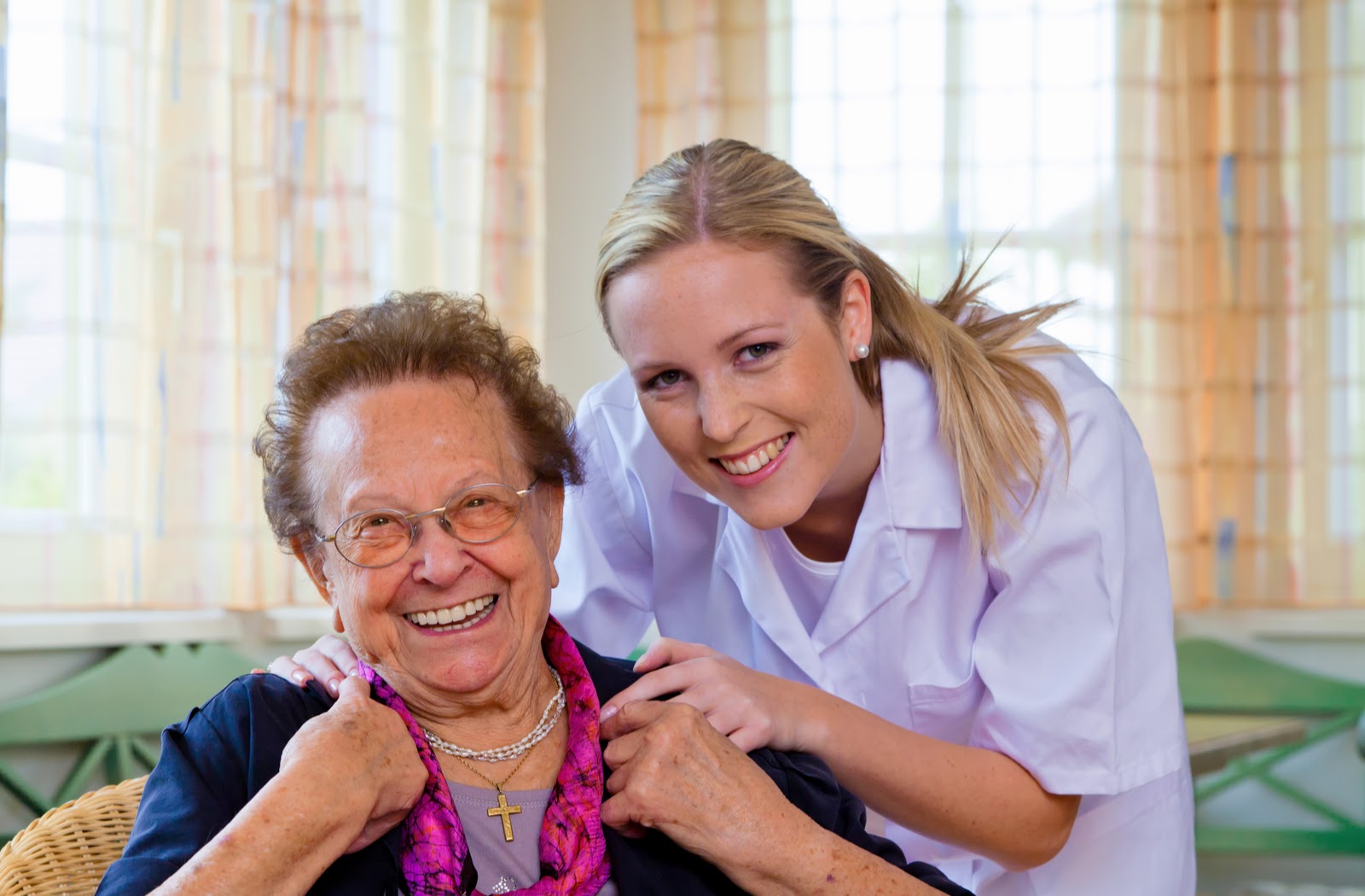Happy nurse and senior women smiling at senior community