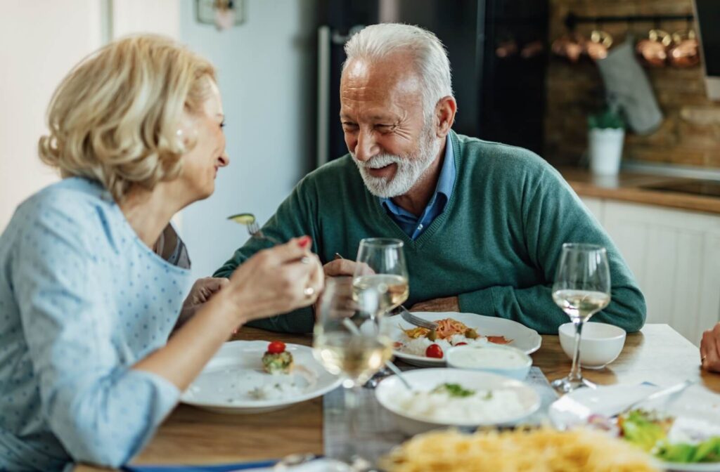 An older couple lovingly looks at one another and smiles during a quiet dinner together in their new home in senior living